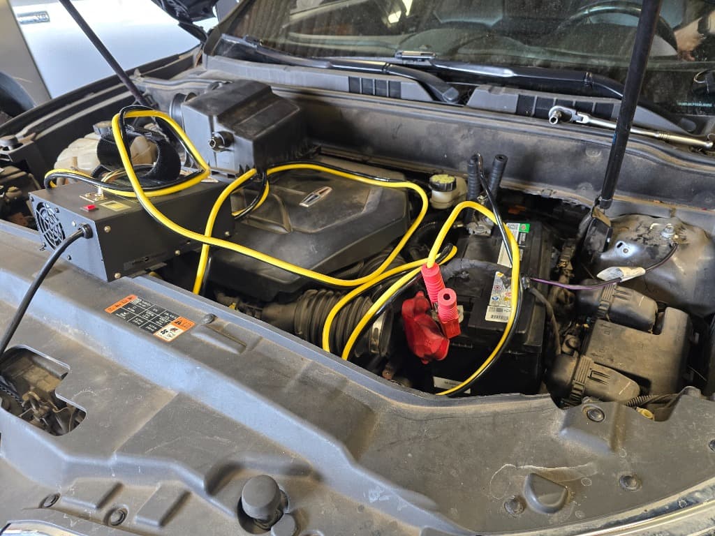 Diagnostic equipment connected to a vehicle battery during testing at Benchmark Automotive Service